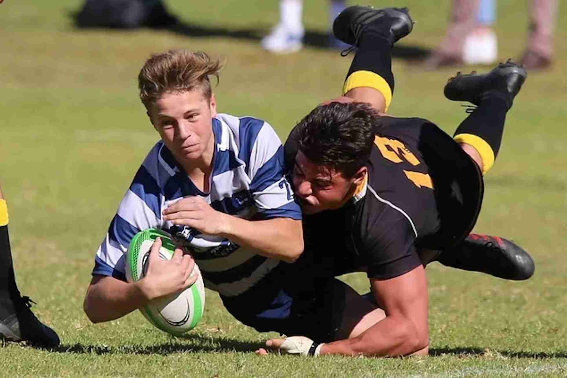 rugby player gets tackled with the ball